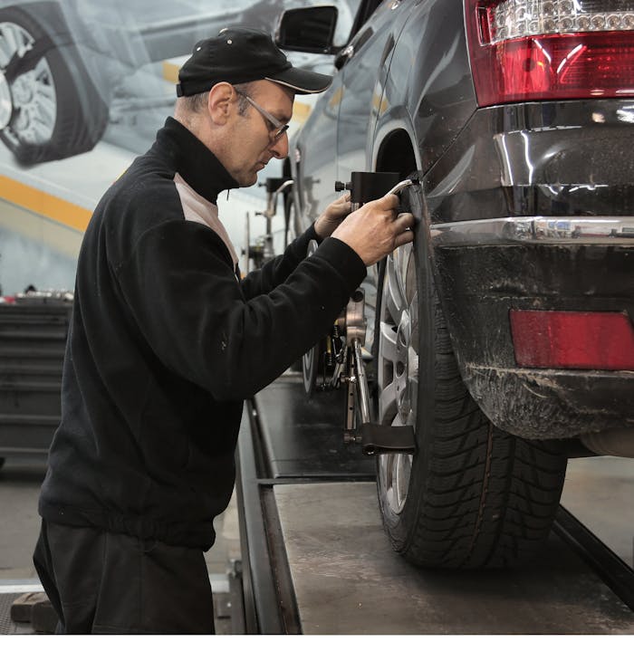 Professional mechanic adjusting wheel alignment for optimal performance in auto repair shop.